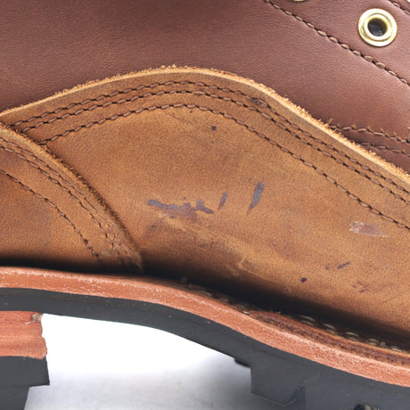 Close-up of a brown leather shoe showing the interior lining, stitching, a brass grommet, and part of the black outsole.