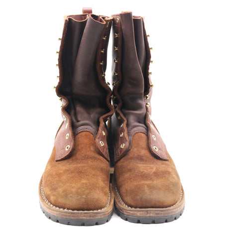 A pair of mid-calf brown suede boots with dark brown leather shafts, brass-tone metal studs, and decorative eyelets, shown against a plain white background.