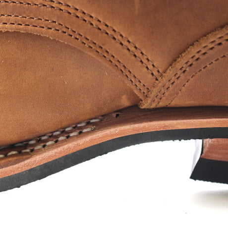 Close-up of a brown leather boot showing the heel area with decorative stitching, a tan insole, and a black outsole against a white background.