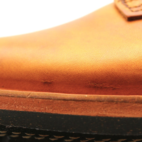 Close-up of a tan leather boot showing the side panel, stitching, and a portion of the black outsole.