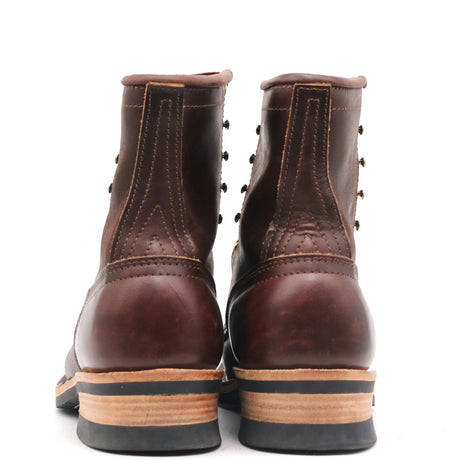 A pair of dark brown leather lace-up ankle boots shown from the back, featuring a stacked sole with a black rubber toe cap, a tan midsole, and a black outsole, set against a plain white background.