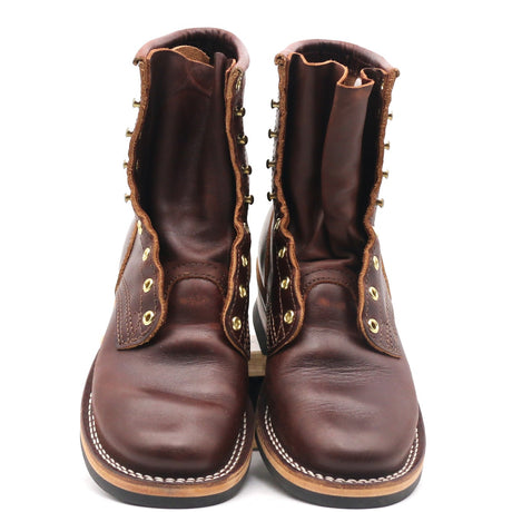 A pair of dark brown leather lace-up boots with brass grommets and white contrast stitching, shown from the front against a white background.