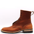 A single brown leather ankle boot with metal eyelets, a pull loop, and a stacked sole, shown from the side on a white background.