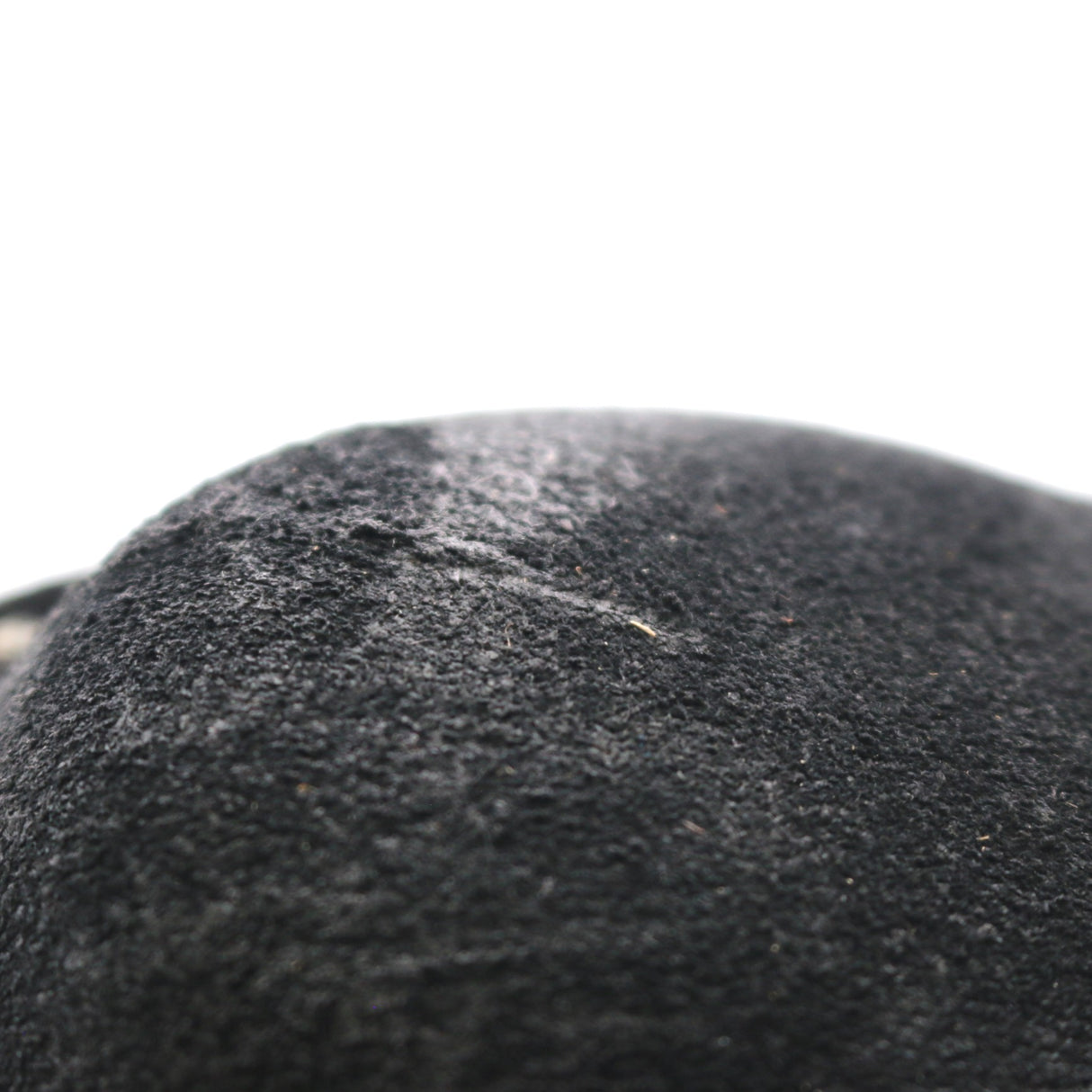 A close-up of a black felt or wool-like textured surface against a plain white background.