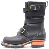A black leather mid-calf boot with double buckle straps, contrast white stitching, and a stacked lug sole with a tan and black heel, shown against a plain white background.