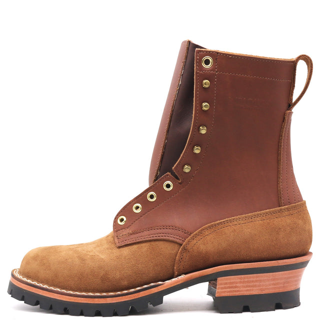 A rugged ankle boot made of brown leather and tan suede, featuring brass eyelets, a stacked wood-look heel, and a black lug sole, shown from a side profile on a white background.