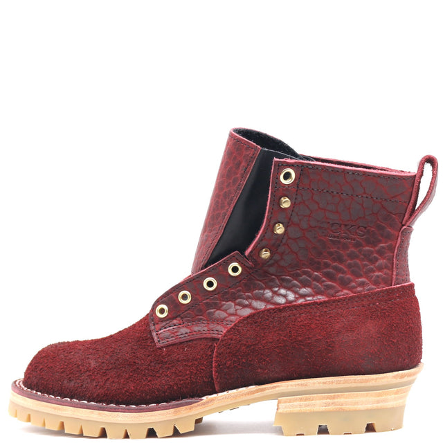 A single red leather ankle boot with a textured embossed pattern on the heel and side panels, a suede-like textured toe and vamp, gold-tone eyelets, and a beige lug sole, shown on a white background.