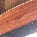 Close-up detail of a brown leather or wood trim piece with visible grain texture, a small dark defect, and a black speckled surface below.