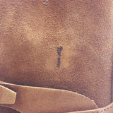 Close-up of a brown suede or nubuck boot material with a small dark stain or scuff visible near the center.