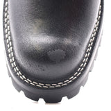 Close-up of a black leather boot toe showing white contrast stitching and a black treaded sole on a white background.