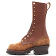 A mid-calf lace-up work boot in brown leather and tan suede, featuring brass eyelets with metal pull tabs, a dark brown lug sole, and a stacked dark heel, shown against a plain white background.