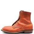 A pair of men's mid-calf leather boots in a warm cognac brown, featuring brass eyelets, lace-up front, and a stacked black sole, shown against a plain white background.