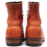 A pair of classic redwing-style leather ankle boots shown from the back, featuring a warm cognac brown leather upper with decorative stitching and a black and brown stacked sole.