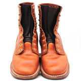 A pair of men's tall brown leather boots with decorative brass grommets and studs, shown from the front against a white background.