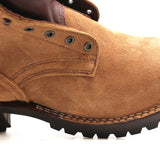 A close-up side view of a tan suede work boot with dark brown stitching, metal eyelets, and a black lug sole on a white background.