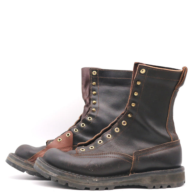 Pair of worn boots with brass hardware and inside lineman patches, shown in front of a white background.