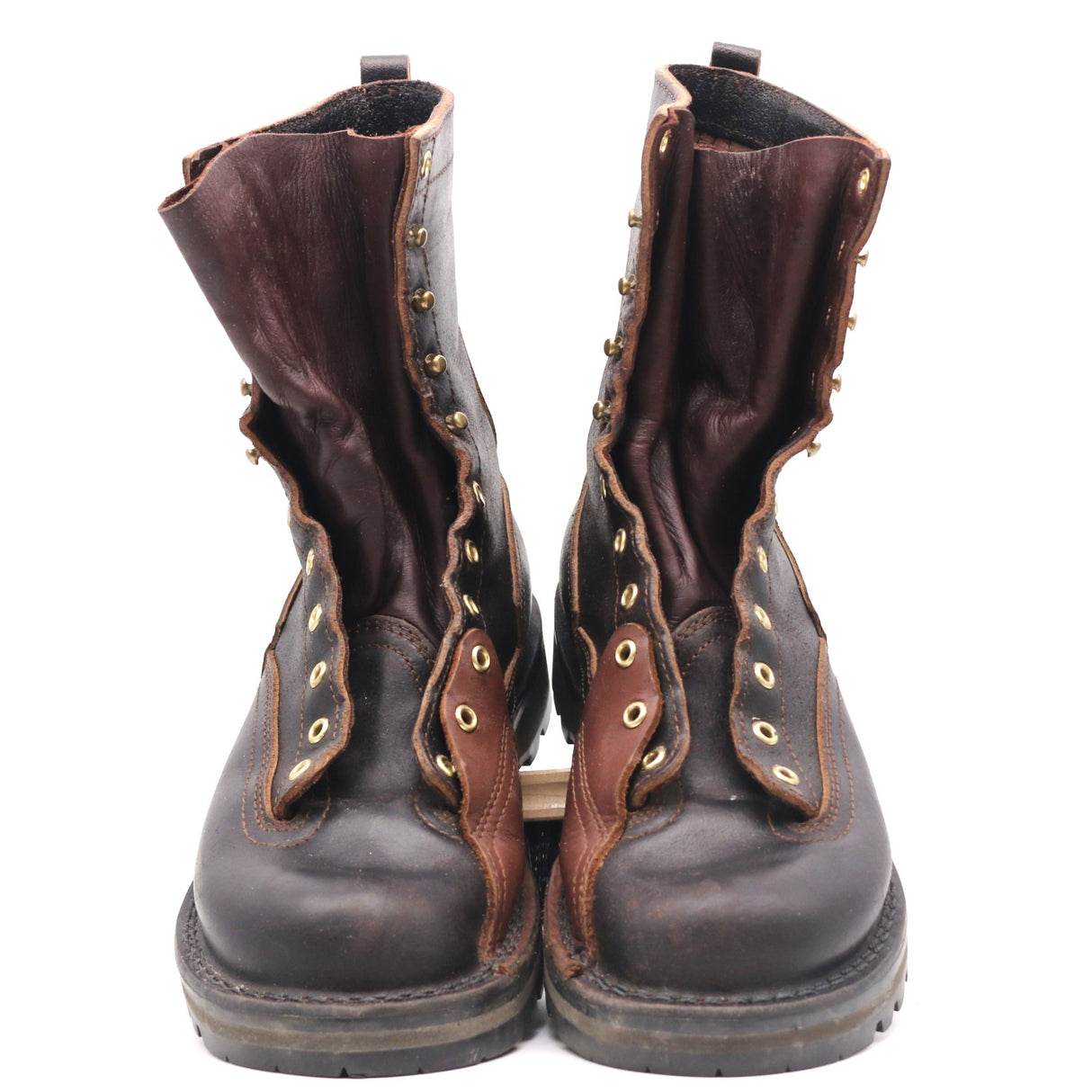 A pair of dark brown leather lace-up boots with brass eyelets and studs, shown from the front against a white background.
