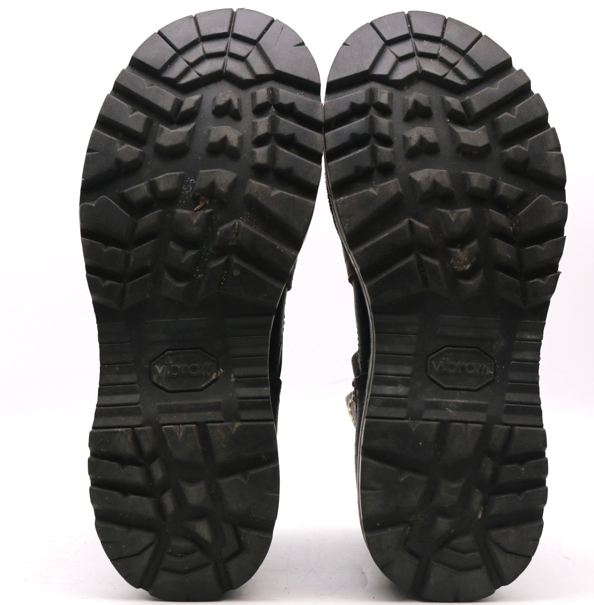 Pair of worn black outsoles with pronounced tread shown against a white background.