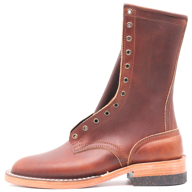 A brown leather lace-up boot with metal eyelets, a stacked sole, and a cork heel, shown from a side profile on a white background.