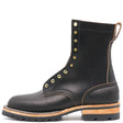 Side profile of a single black eight inch boot with brass hardware in front of a white background.