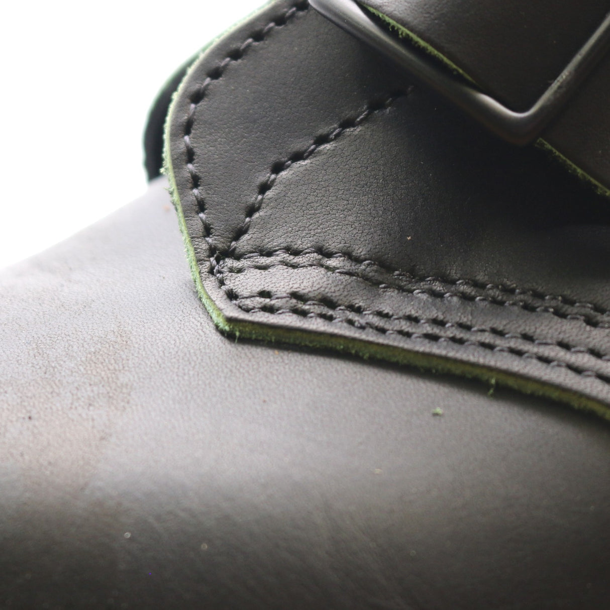 Close up photo of the bluchers on a black tanker boot. The bluchers have some exposed sewing holes.