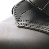 Close up photo of the bluchers on a black tanker boot. The bluchers have some exposed sewing holes.