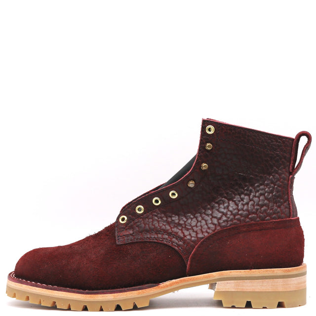 Dark red textured leather boot with brass hardware and honey lug outsole in front of a white background.