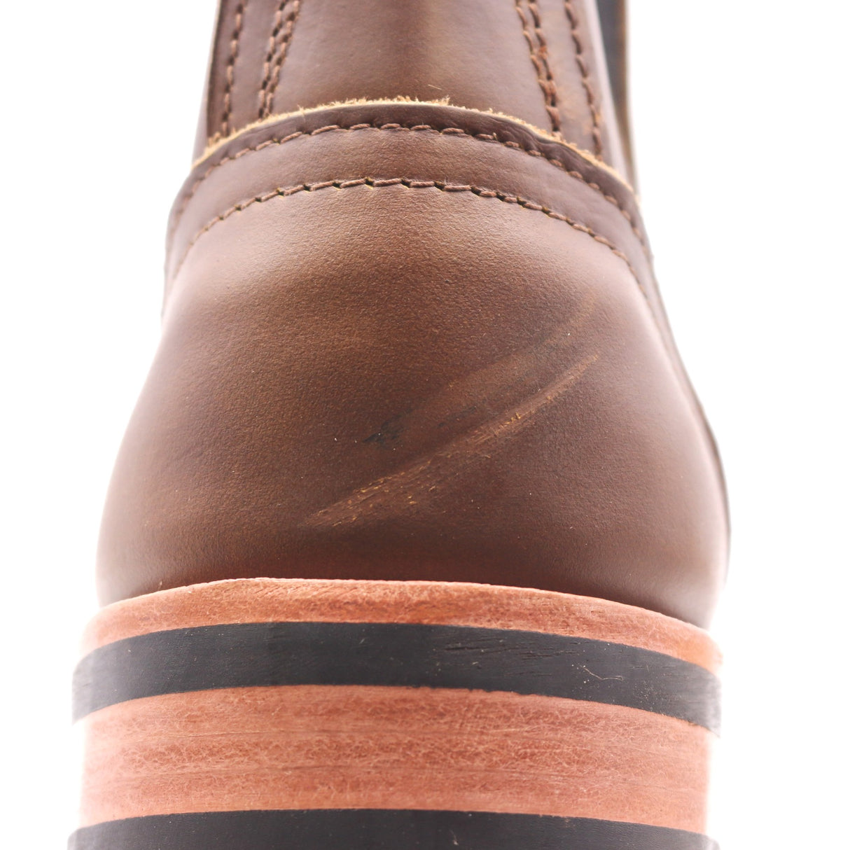 Close up photograph of the heel counter of a brown leather boot. Heel counter has visible scuff marks.