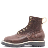 A dark brown textured leather lace-up boot with brass eyelets, a pull loop, and a thick black lug sole, shown against a plain white background.
