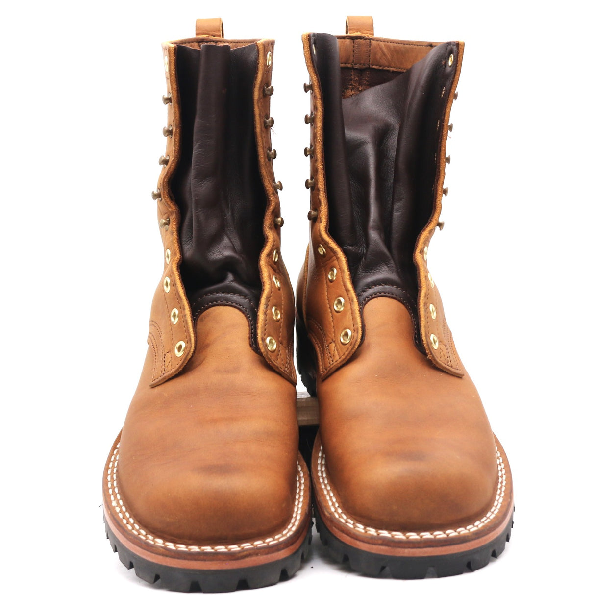 A pair of brown leather lace-up boots with dark brown inner shafts, brass eyelets, and white contrast stitching on the soles, shown against a plain white background.