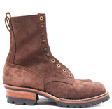A brown suede lace-up boot with a chunky black lug sole, a stacked wood-look heel, and brass eyelets, shown from a side profile on a white background.