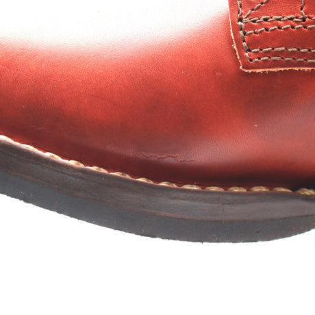 Close-up of a reddish-brown leather boot showing the toe, stitching, and a portion of the dark sole against a white background.