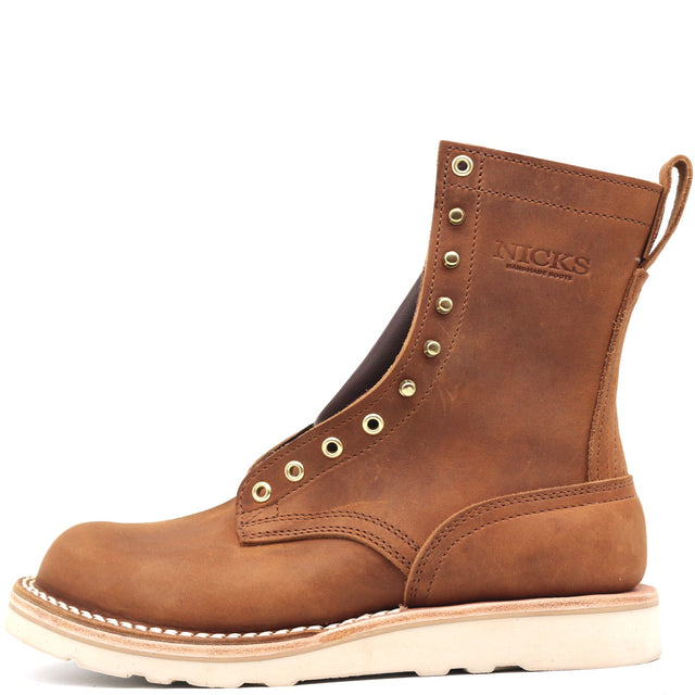 A brown leather ankle boot with gold-tone metal eyelets, a pull tab, and a thick off-white sole, shown from a side profile on a white background. The brand name 'NICKS' is embossed on the side.