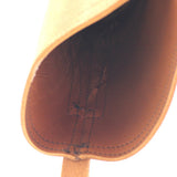 Close-up of the interior opening of a tan leather shoe or boot, showing the brown footbed and dark stitching against a white background.