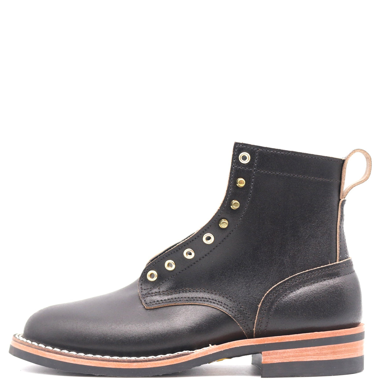 A black leather ankle boot with gold-tone metal eyelets, contrast stitching, and a stacked black sole with a tan outsole, shown from a side profile on a white background.