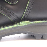 Close-up of a black leather boot showing a heavily worn, frayed, and damaged green sole edge.