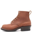 A brown leather ankle boot with brass eyelets, a low black block heel, and a pull tab, shown from a side profile on a white background. The brand name 'NICKS' is embossed on the side.
