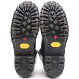 Pair of black boot outsoles with visible wear, shown against a white background.