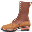 Tall brown work boot with brass hardware and a lug outsole in front of a white background.