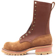 Tall brown leather work boot with honey lug outsole, brass hardware, and rear pull loop in front of a white background.