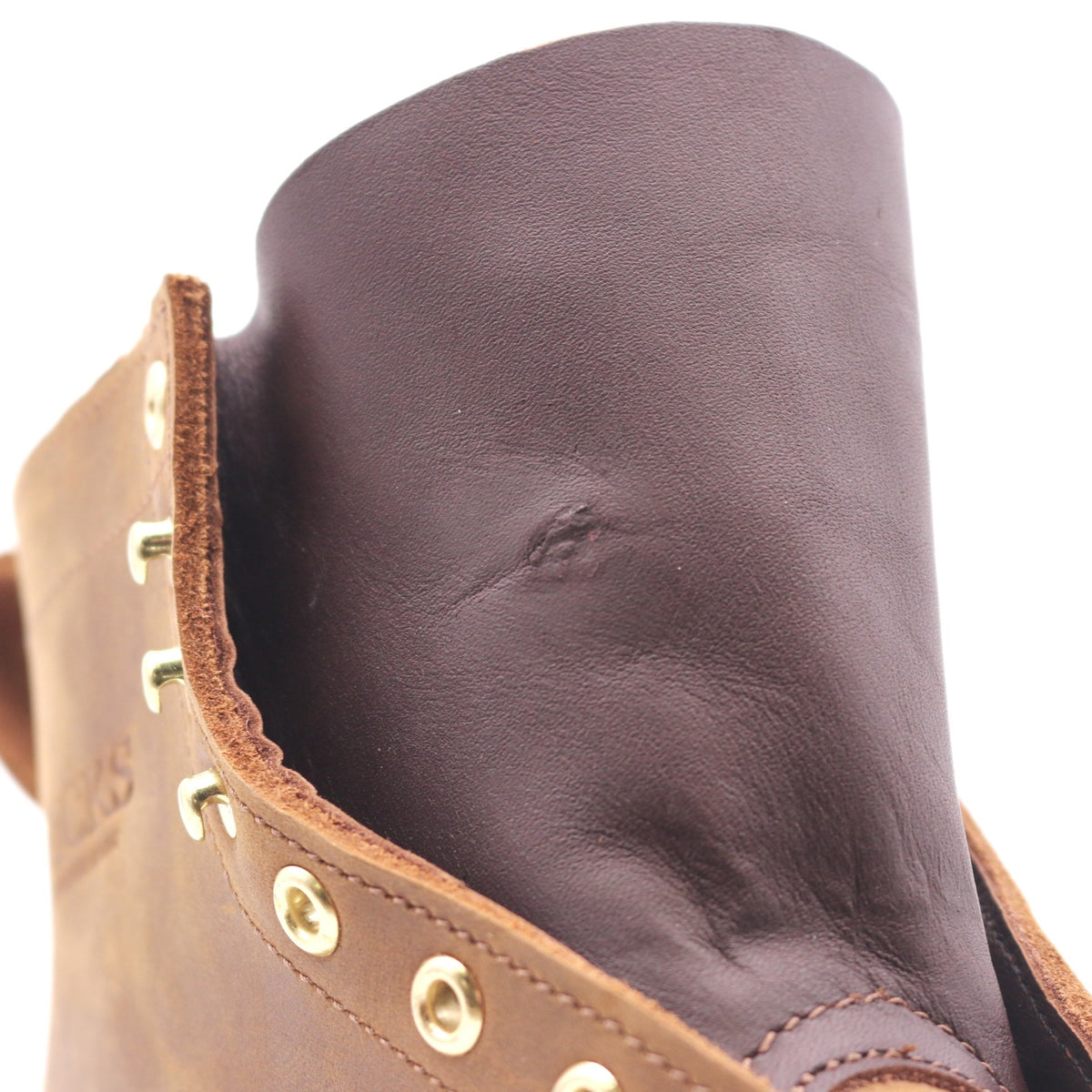 Close up of a leather boot gusset. Evidence of a patched hole can be seen in the leather.
