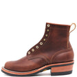 Brown leather boot with rolled top, brass hardware, and rear pull loop in front of a white background. Boots have visible factory damage such as scrapes and dents in the leather.