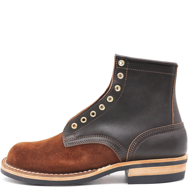 A single ankle boot shown in a side profile on a white background. The boot features a dark brown leather upper with a contrasting medium brown suede toe cap and heel panel, accented by brass eyelets and stitching.