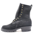 A black ankle combat boot featuring a textured faux-croc leather shaft, a black suede toe and heel counter, gold-tone metal eyelets, and a chunky lug sole.