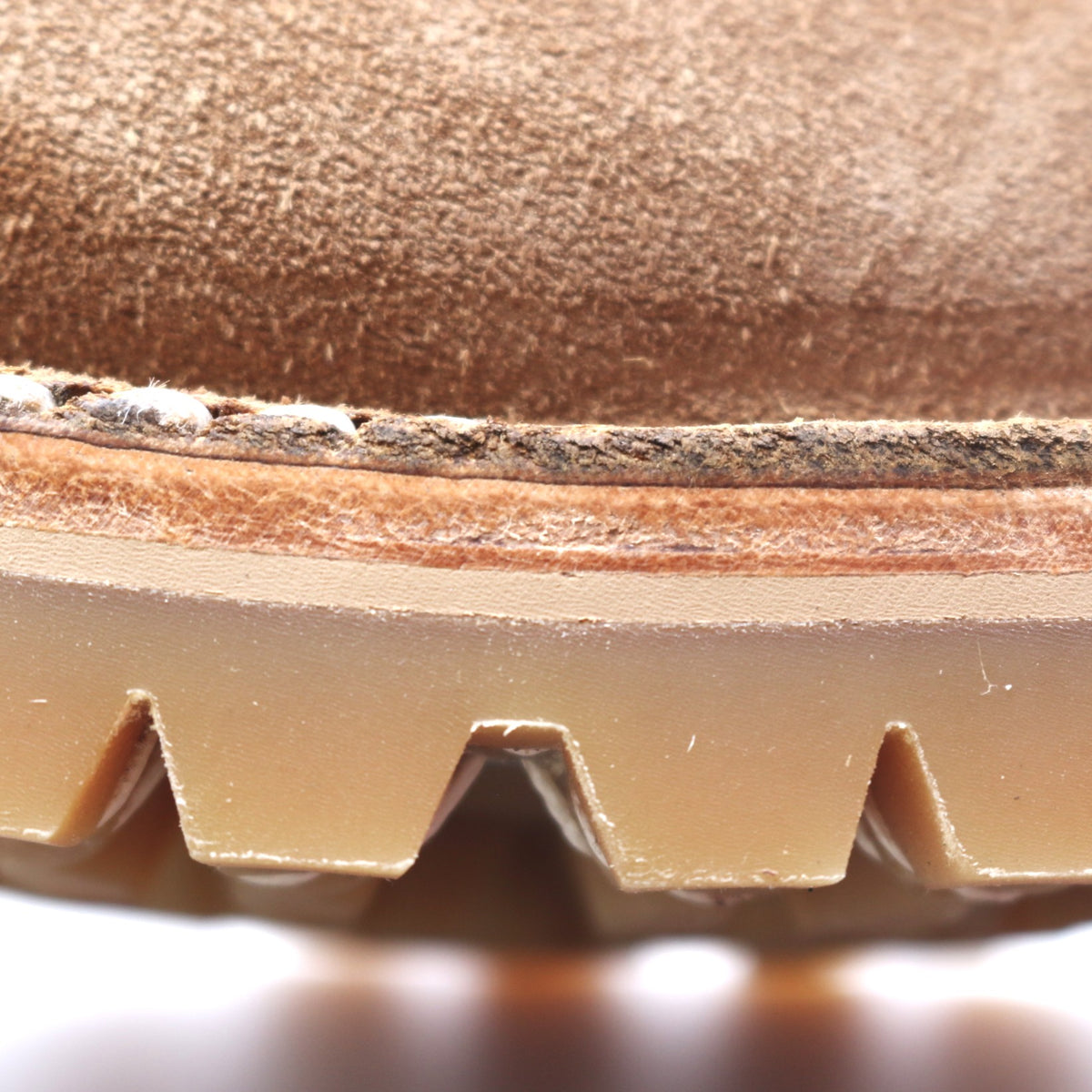 Close up image of a leather midsole of a brown leather boot above the outsole. Image shows noticeable cracking in the leather.
