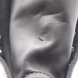 Close-up of a black leather boot or shoe showing the textured leather surface, stitching, and small gold-tone studs along the side.