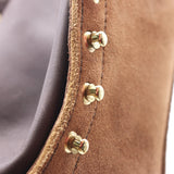 Close-up detail of a brown suede or leather strap with brass-tone rivets and a dark brown inner lining.