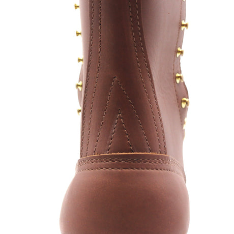 Close-up of a brown leather boot featuring decorative gold-tone studs and stitching on a white background.