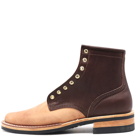 Photo of a light brown and dark brown two-tone leather ankle boot with brass hardware in front of a white background.