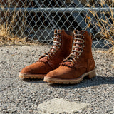 Shrunken bison brown leather Bear Slayer with brown padded collar, honey vibram outsole and 4 relief notches. Boots sitting on gravel outside in front of chain link fence.